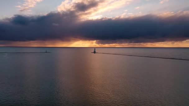 美しい日没の空中上昇し ミシガン湖の穏やかな水を反映して 上記のオレンジ色の空と雲と白い色のラディントン防波堤灯台に向かって飛んで — ストック動画