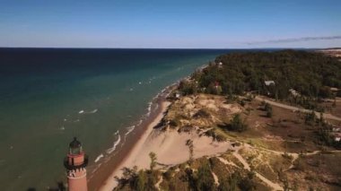 Küçük Samur Deniz Feneri 'nden uçarak uzaklaşan güzel hava manzarası Michigan Gölü kıyıları boyunca ağaçlarla kaplı kumulların ve bitki örtülerinin arasında dalgalar içeri girerken açık mavi gökyüzü..