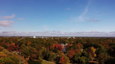 Roger Williams Parkı 'ndaki göllerden birinin üzerine güzel bir sonbahar havası iniyor. Ön planda ağaçlar ve ufukta rüzgâr türbinleri görünüyor..