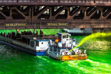Chicago, IL - 13 Mart 2021: Shoreline View 's Cityview teknesi DuSable Köprüsü' nün altından geçerken Tesisatçılar 130 su çekmek ve St. Patrick Günü 'nde nehri yeşile boyamak için yol alıyor..