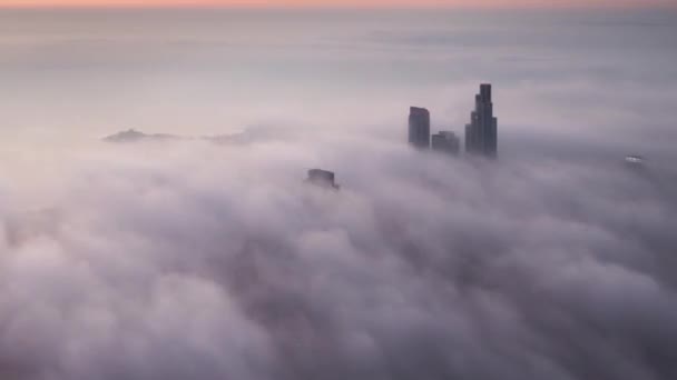 天気が暖まり始め 太陽が下の雲の上にピンクとオレンジの色合いを投げかけるので ミシガン湖に向かって日の出に都市に圧延濃霧の空中シカゴ時間の経過をパンニング — ストック動画