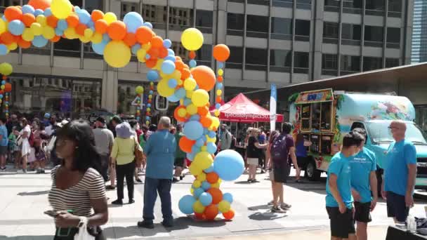 Chicago, IL - August 5th, 2021: A large colorful balloon arch, activity and information booths and music greet people attending the annual Special Olympics Illinois Ducky Derby in downtown. — Stock Footage Chicago August 5Th 2021 Large Colorful Balloon Arch Activity Information Stock Video