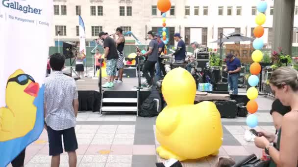Chicago, IL - August 5th, 2021: The band 90's Pop Nation plays music at Pioneer Court plaza prior to the annual Special Olympics Ducky Derby race and fundraising event. — Stock Footage Chicago August 5Th 2021 Band Pop Nation Plays Music Pioneer Royalty Free Stock Video