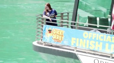 Chicago, IL - 5 Ağustos 2021: Ducky Derby elçisi Mallory Taylor, her yıl düzenlenen Özel Olimpiyatlar bağış etkinliği sırasında bitiş çizgisindeki teknenin arkasındaki suya bakıyor..