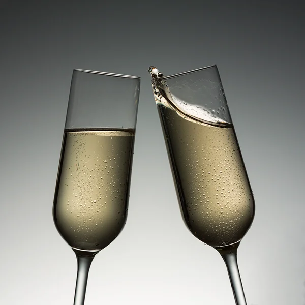 Clink glasses with champagne splash — Stock Photo, Image