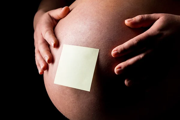 Pregnant woman caressing her belly with Sticky Note — Stock Photo, Image