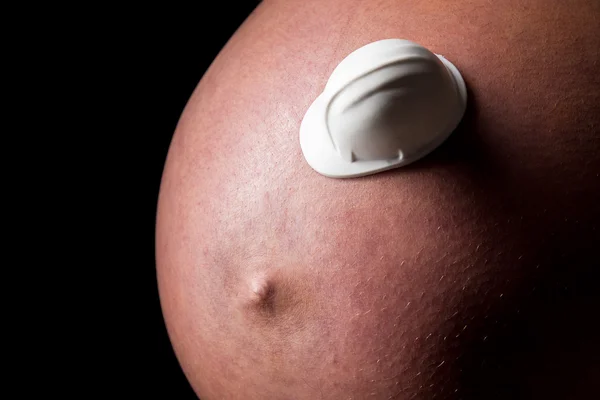 Belly of pregnant woman with construction helmet — Stock Photo, Image