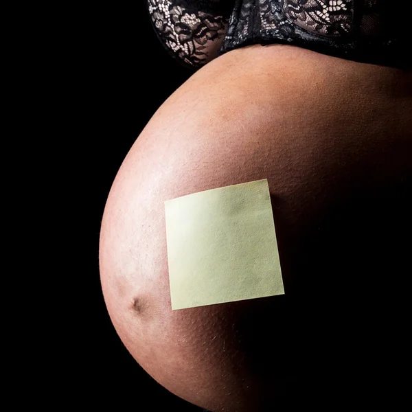 Belly of pregnant woman with note — Stock Photo, Image