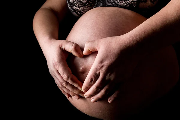 Pregnant woman holding her hands in heart shape — Stock Photo, Image