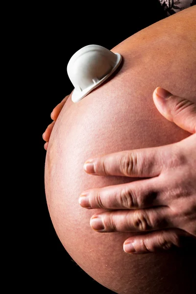 Belly of pregnant woman working helmet — Stock Photo, Image