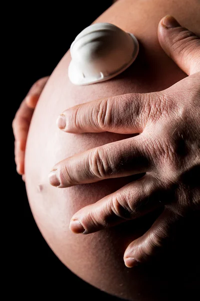 Hands holding a belly of pregnant woman with worker helmet — Stock Photo, Image