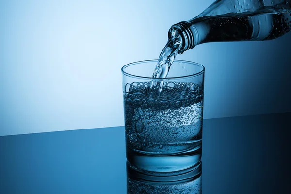 Mineraal water gieten in met een glas — Stockfoto