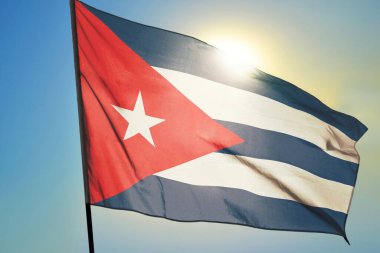 Küba bayrağı güneşin önünde rüzgarda dalgalanıyor.