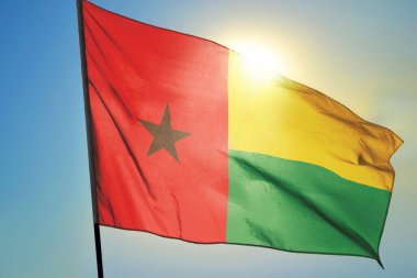 Gine-Bissau bayrağı güneşin önünde rüzgarda dalgalanıyor.