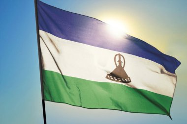 Lesotho bayrağı güneşin önünde rüzgarda dalgalanıyor.