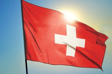 İsviçre bayrağı güneşin önünde rüzgarda dalgalanıyor