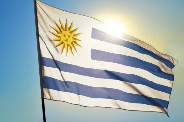 Uruguay bayrağı güneşin önünde rüzgarda dalgalanıyor.