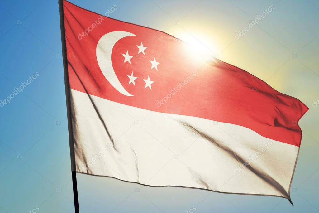 Singapore flag waving on the wind in front of sun