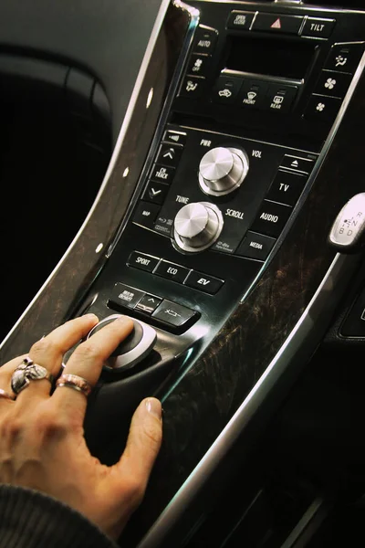 A luxury car control panel close up with a hand on a joystick