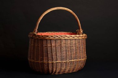 Tek kulplu, sade örülmüş bir sepet ve koyu arkaplana karşı sunulan canlı kırmızı-turuncu bir yolcu gemisi. Hasat, piknik ya da geleneksel dekor için mükemmel..