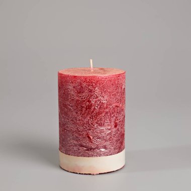 Canlı, yanmayan kırmızı sütun mumu düz bir zemine karşı dimdik ayakta duruyor. Dokulu, kırsal yüzeyi ve kremalı tabanı sıcaklık ve zarafet ekler, ev dekorasyonu, ambiyans veya şenlik ortamları için mükemmeldir..