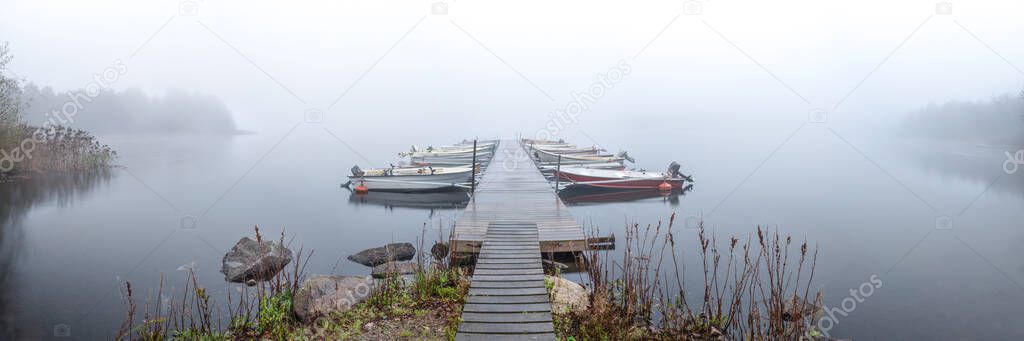 Panoramic image of foggy morning on the pier with the boats