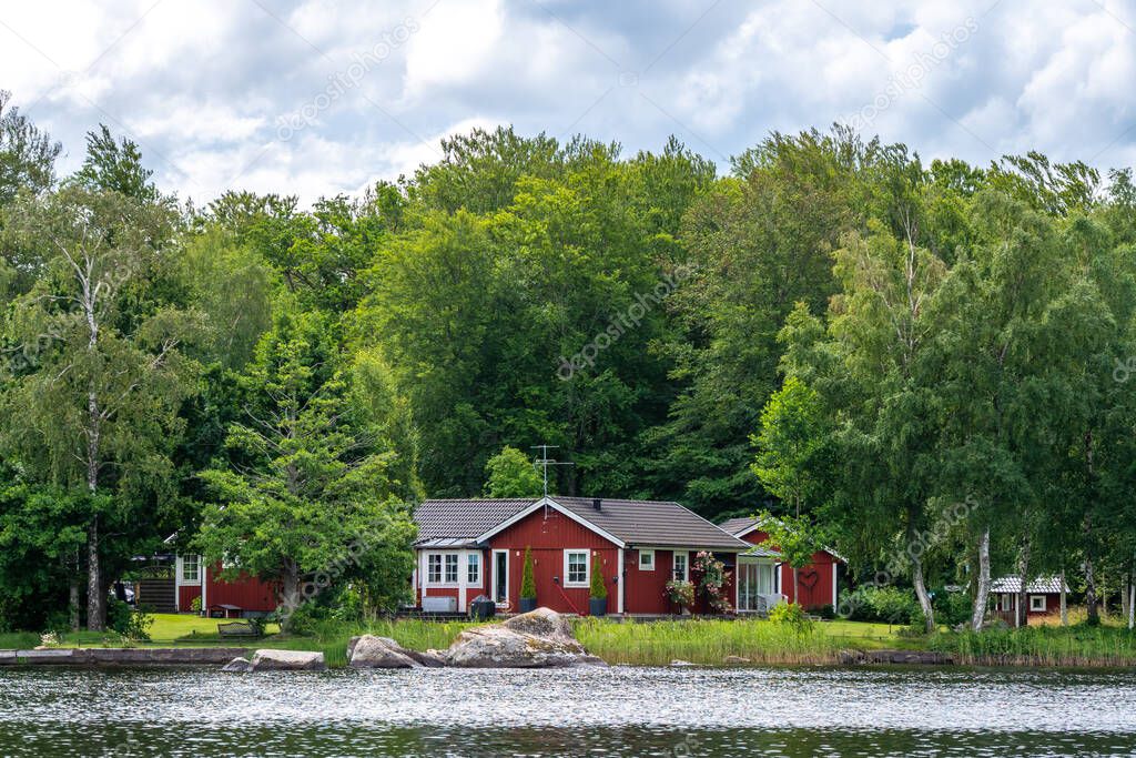 View on red holiday cabin by a lake in Stockholm archipelago, Sweden