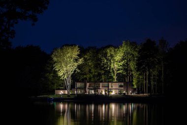 Göl kenarındaki modern evin gece görüntüsü.