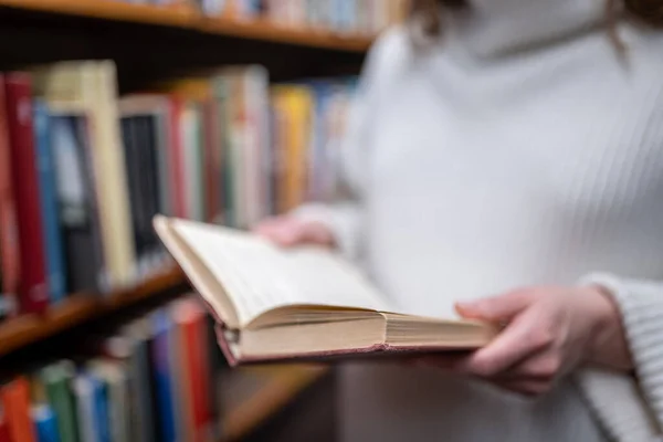 Jovem segurando livro velho na biblioteca — Fotografia de Stock