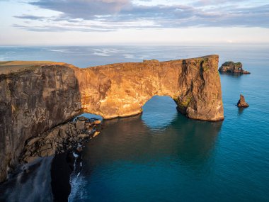 Amazing black arch of lava standing in the sea. Location cape Dyrholaey, Iceland clipart