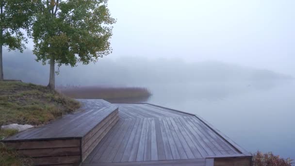 Panning view of morning foggy pier on the lake with wooden boats — Stock Video