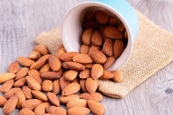 Almonds in bowl on wooden table.