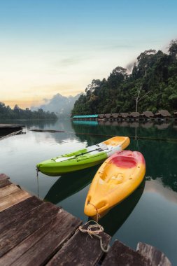 Güneşin doğuşunda kanoyla güzel bir sabah manzarası ve Tayland 'ın Surat Thani Eyaleti' ndeki Khao Sok Ulusal Parkı 'ndaki Ratchaprapha Barajı' nda doğal eğlence.