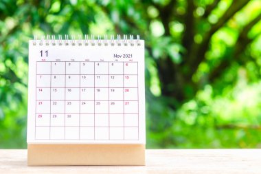 Kasım ayı, Takvim masası 2021 planlama ve hatırlatma için ahşap masa üzerinde yeşil doğa arka planı ile.