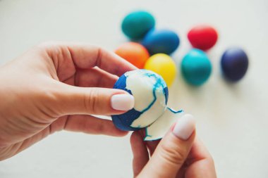 Yumurtalar. Paskalya. Paskalya yumurtaları. Renkli yumurta. Beyaz arka planda yumurtalar. Yumurta kabuğu. Kız bir yumurta temizliyor. Kız elleri.