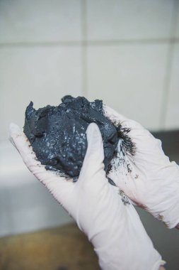Doktorun ellerinde iyileştirici çamur var. Beyaz eldivenli eller. Beyaz paltolu bir adam..