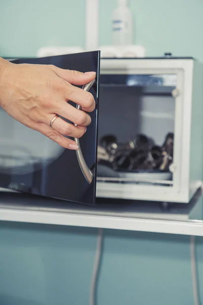 Kadın eli gardırobu açar. Tıbbi aletlerin sterilize edilmesi için kuru ısı. Cam dolap açık. Jinekoloğun tıbbi aletleri yalan söylüyor..