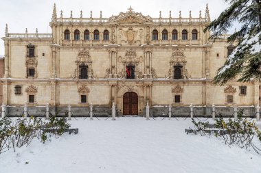 horizontal view of main facade of major college of saint ildefonso and san diego square in the city of alcala de henares snowy covered clipart