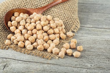 Ahşap masadaki tahta kaşıkta kurutulmuş nohut. Bir yığın baklagil nohut. Sağlıklı ve doğal vejetaryen yemekleri..