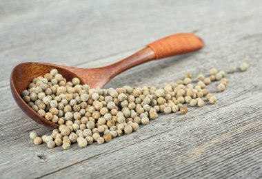 Ahşap arka planda tahta kaşıkta beyaz biber. Beyaz biberler..