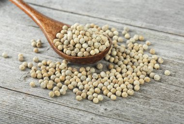 Ahşap arka planda tahta kaşıkta beyaz biber. Beyaz biberler..