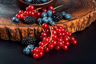 Kil kasede taze böğürtlen, siyah ahşap masada. Frenk üzümü, yabanmersini ve böğürtlen.