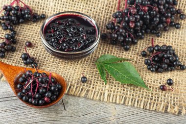 Taze olgun siyah mürver, mürver şurubu ve kırsal ahşap arka planda mürver yaprakları. Alternatif tıp ve yaşam tarzı.