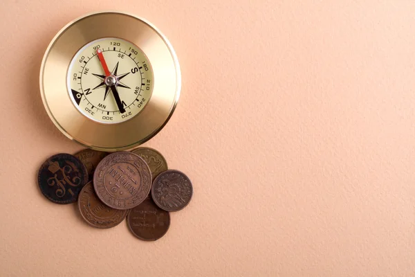 Компас зі старими монетами на коричневому фоні — стокове фото