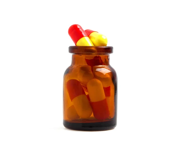 Medicin glasflaska med färgade piller, isolerade på vit baksida — Stockfoto