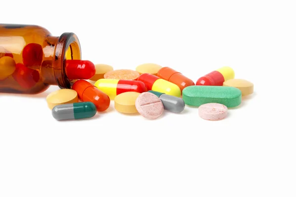 Pilules colorées, comprimés et flacon de médicaments sur fond blanc — Photo