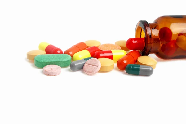 Pílulas coloridas, comprimidos e garrafa em um fundo branco — Fotografia de Stock