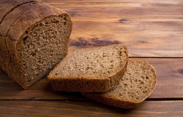 Bochenek chleba żytniego w plasterkach na rustykalne drewniane tła — Zdjęcie stockowe