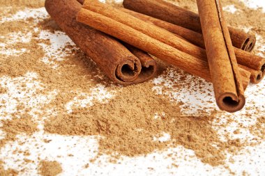 Tarçın ile onun etrafında toz beyaz bir arka plan üzerinde sopa