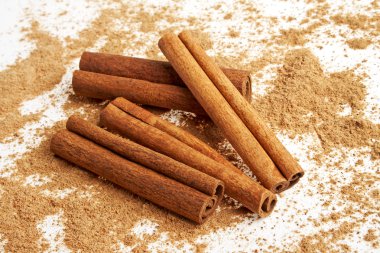 Tarçın ile onun etrafında toz beyaz bir arka plan üzerinde sopa